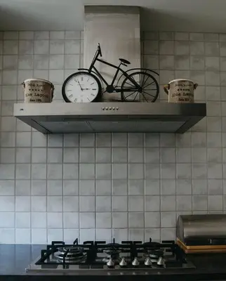 a clock and a bike on a shelf above a stove at Perla di Robbie in Zandvoort
