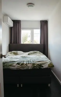 a bedroom with a bed in front of a window at Perla di Robbie in Zandvoort