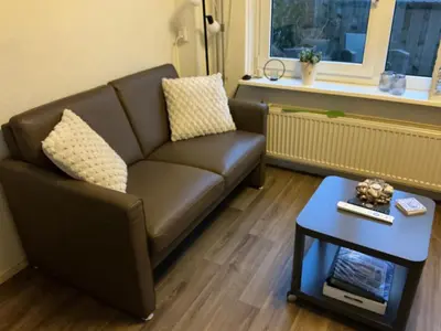 a living room with a brown couch and a table at Zomerhuis Zwart in Egmond aan Zee