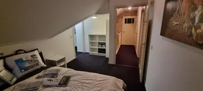 a bedroom with a bed and a hallway with a staircase at Ruime vakantievilla in Zeewolde in Zeewolde