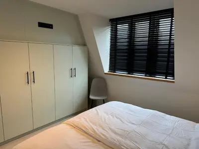 a bedroom with white cabinets and a bed and a window at Casa del Cisne 4 in Zandvoort