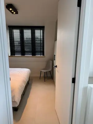 a bedroom with a bed and a chair and a window at Casa del Cisne 4 in Zandvoort