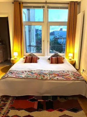 a bedroom with a large bed with a large window at Canal House with a Unique View in Amsterdam
