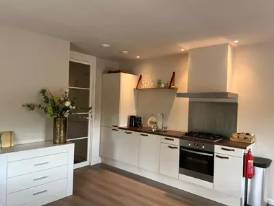 a kitchen with white cabinets and a stove top oven at Luxury Private Spa with golden bath, cinema and sauna in Bodegraven