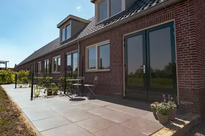 a brick building with large glass doors and a patio at Logeer aan de Geer in Wilnis