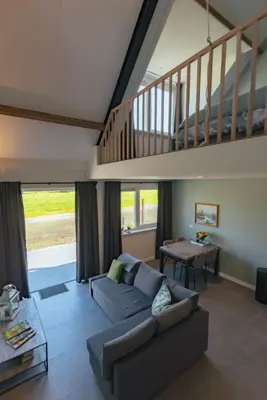 a living room with a couch and a staircase at Logeer aan de Geer in Wilnis
