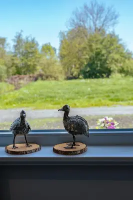 two bird statues sitting on a window sill at Logeer aan de Geer in Wilnis