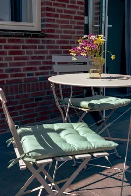 a table and chairs with a vase of flowers on it at Logeer aan de Geer in Wilnis