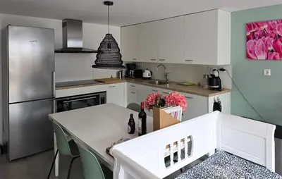 a kitchen with white cabinets and a table and a refrigerator at 1 Bedroom Lovely Home In Heiloo in Heiloo