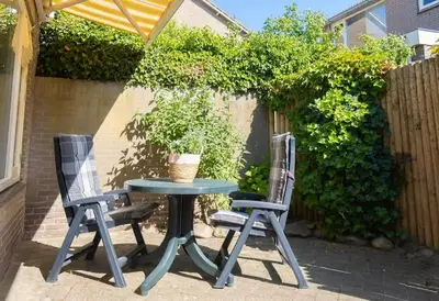 two chairs and a table in a patio at Duinrust in Egmond aan Zee