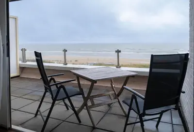 a table and two chairs on a balcony with the beach at Seaviews Egmond in Egmond aan Zee