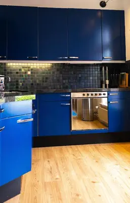 a blue kitchen with blue cabinets and a wooden floor at Verdronkenoord57 in Alkmaar