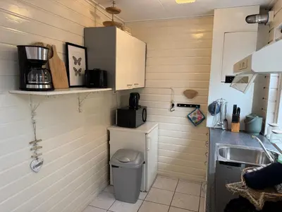 a small kitchen with a sink and a microwave at Zon Zee en Duin Egmond Strandhuisje in Egmond aan Zee
