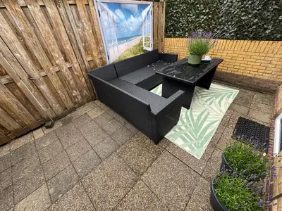 a patio with a black bench and a table at Zon Zee en Duin Egmond Strandhuisje in Egmond aan Zee