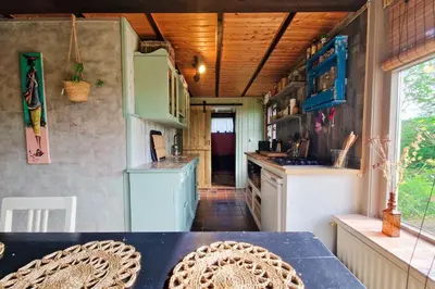a small kitchen with a table in a tiny house at Vakantiehuisje Casa Calida in Warmenhuizen