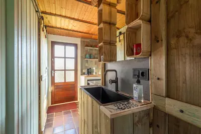 a kitchen with wooden cabinets and a sink in a room at Vakantiehuisje Casa Calida in Warmenhuizen