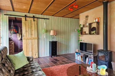 a living room with a couch and a tv at Vakantiehuisje Casa Calida in Warmenhuizen