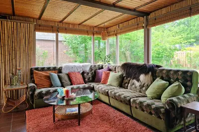 a living room with a large couch with colorful pillows at Vakantiehuisje Casa Calida in Warmenhuizen