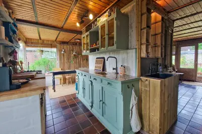 a kitchen with green cabinets and a sink at Vakantiehuisje Casa Calida in Warmenhuizen