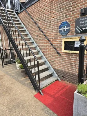 a staircase with a red carpet next to a brick building at B&B La Clé Lopik in Lopik