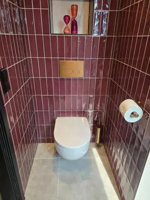 a bathroom with a toilet in a purple tiled wall at B&B La Clé Lopik in Lopik