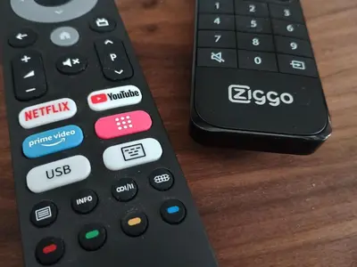 two remote controls sitting on top of a wooden table at Het Haven Huysje in Hoorn