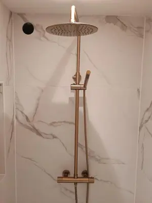 a brass floor lamp in a bathroom with a marble wall at Het Haven Huysje in Hoorn