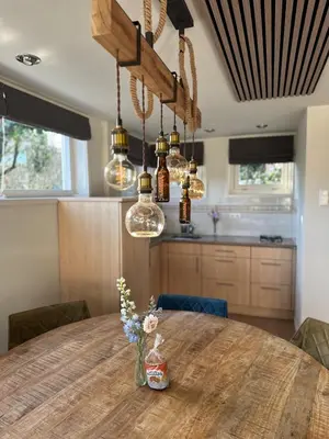 a dining room with a wooden table and lights at Cozy Guesthouse 15 min Amsterdam Haarlem Zandvoort in Zwanenburg