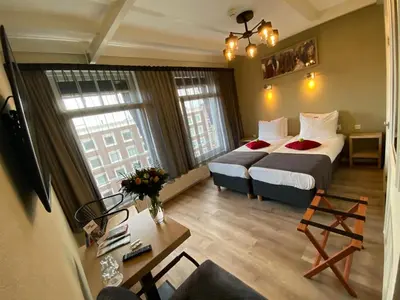 a hotel room with two beds and a table at Alp Hotel in Amsterdam