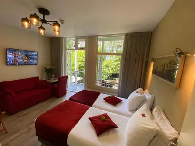 a bedroom with a large bed and a red couch at Alp Hotel in Amsterdam