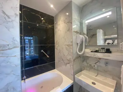a bathroom with a tub and a sink and a mirror at Alp Hotel in Amsterdam