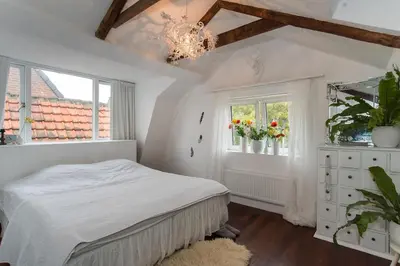 a bedroom with a bed and a window and a chandelier at Cosy real Dutch family house anno 1910 in Alkmaar