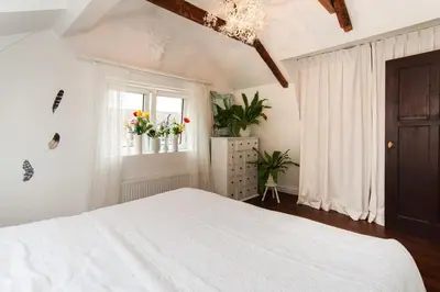 a white bedroom with a bed and a window at Cosy real Dutch family house anno 1910 in Alkmaar