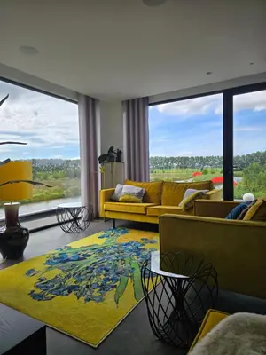 a living room with a yellow couch and a large window at Villa Suite Oudshoorn in Alphen aan den Rijn