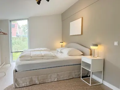 a white bedroom with a bed and a window at Vakantiehuis voor mindervaliden op Recreatiepark De Wielen - 61 in Sint Maarten