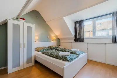 a bedroom with a bed and a large window at Vacation home Oase in Egmond aan Zee
