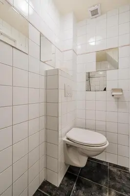 a white bathroom with a toilet and a mirror at Vacation home Oase in Egmond aan Zee