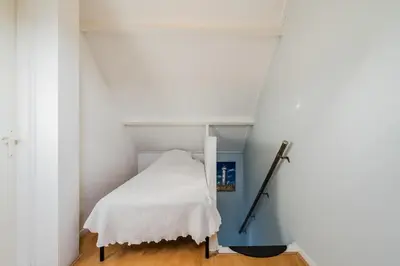 a small bedroom with a bed in a white room at Vacation home Oase in Egmond aan Zee