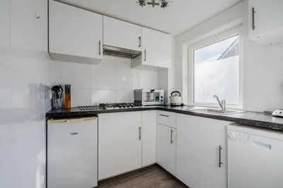 a white kitchen with white cabinets and a window at Vacation home Oase in Egmond aan Zee