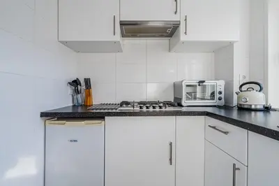 a white kitchen with white cabinets and a microwave at Vacation home Oase in Egmond aan Zee