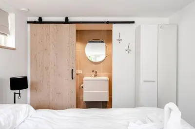 a bedroom with a sink and a door with a mirror at Fazantisch Studio for 2 with private parking in Zandvoort