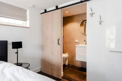 a bedroom with a sliding door leading to a bathroom at Fazantisch Studio for 2 with private parking in Zandvoort