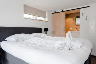a large white bed with white sheets and pillows at Fazantisch Studio for 2 with private parking in Zandvoort