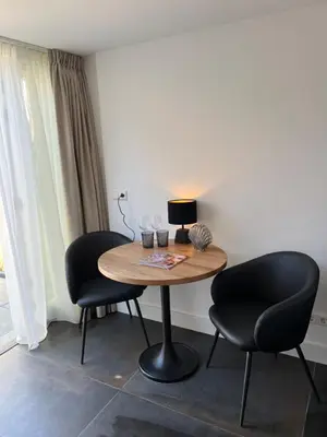 a table with two chairs and a lamp on it at Fazantisch Studio for 2 with private parking in Zandvoort