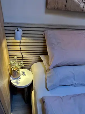 a bed with a side table next to a bed with a lamp at Studio Oranje Nassau aan Zee in Zandvoort