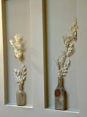 two vases with flowers in them on a shelf at Studio Oranje Nassau aan Zee in Zandvoort