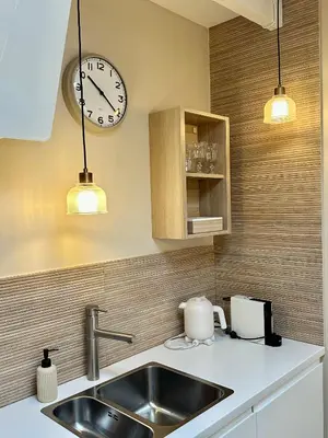 a kitchen with a sink and a clock on the wall at Studio Oranje Nassau aan Zee in Zandvoort