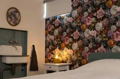 a bedroom with a flower wallpaper with a candle on a table at Boerenvakantie in Hilversum