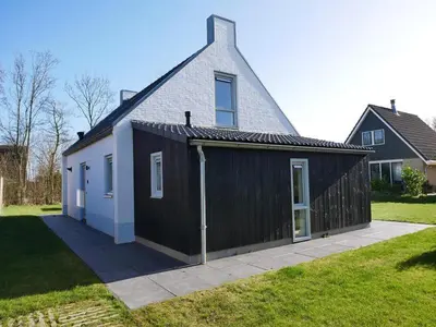a house with a black and white garage at Vakantiehuis met sauna op Recreatiepark de Wielen - 64 in Sint Maarten