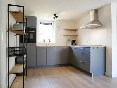 a kitchen with blue cabinets and a window at Vakantiehuis met sauna op Recreatiepark de Wielen - 64 in Sint Maarten